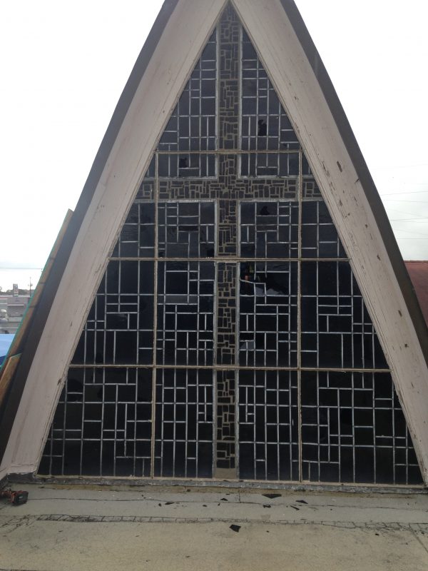 The massive cross stained glass has multiple large holes from hail damage